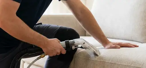 Professional upholstery cleaner deep-cleaning a fabric sofa with a handheld extraction tool, Milwaukee, WI.